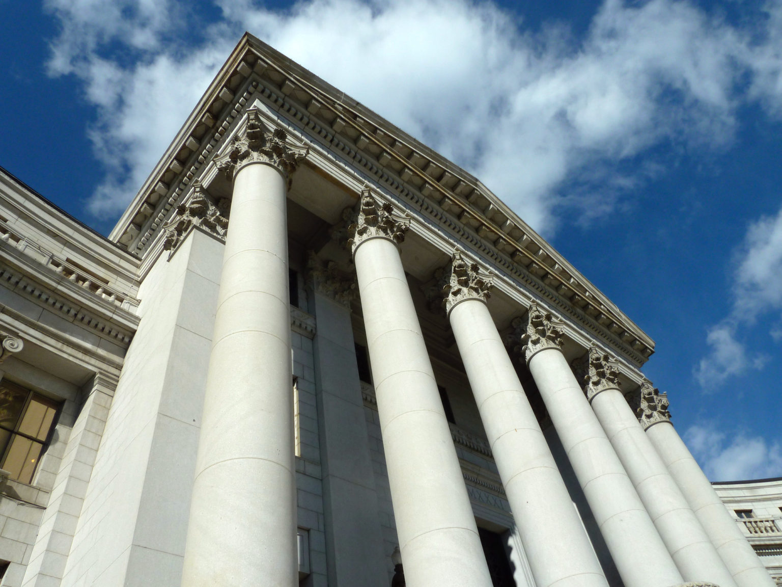 Stone columns of a courthouse against a blue sky