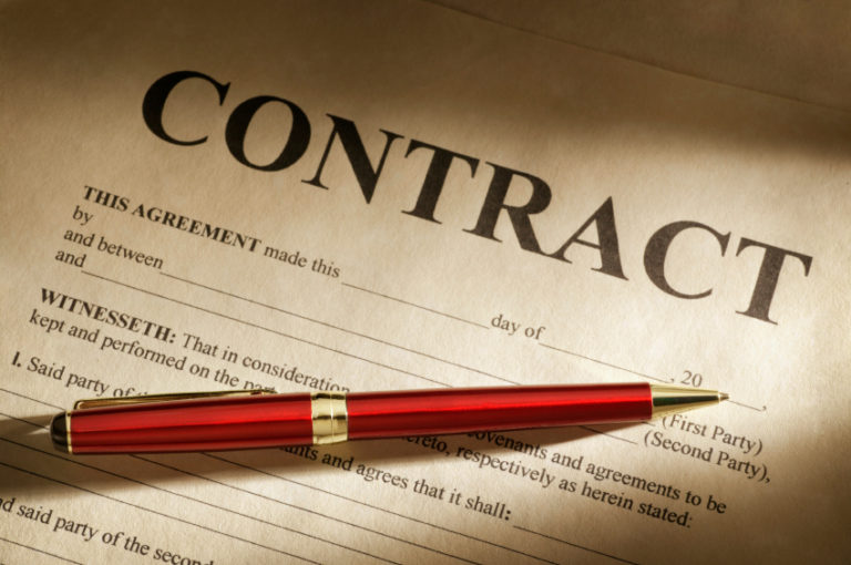 A red pen lying across a printed contract agreement