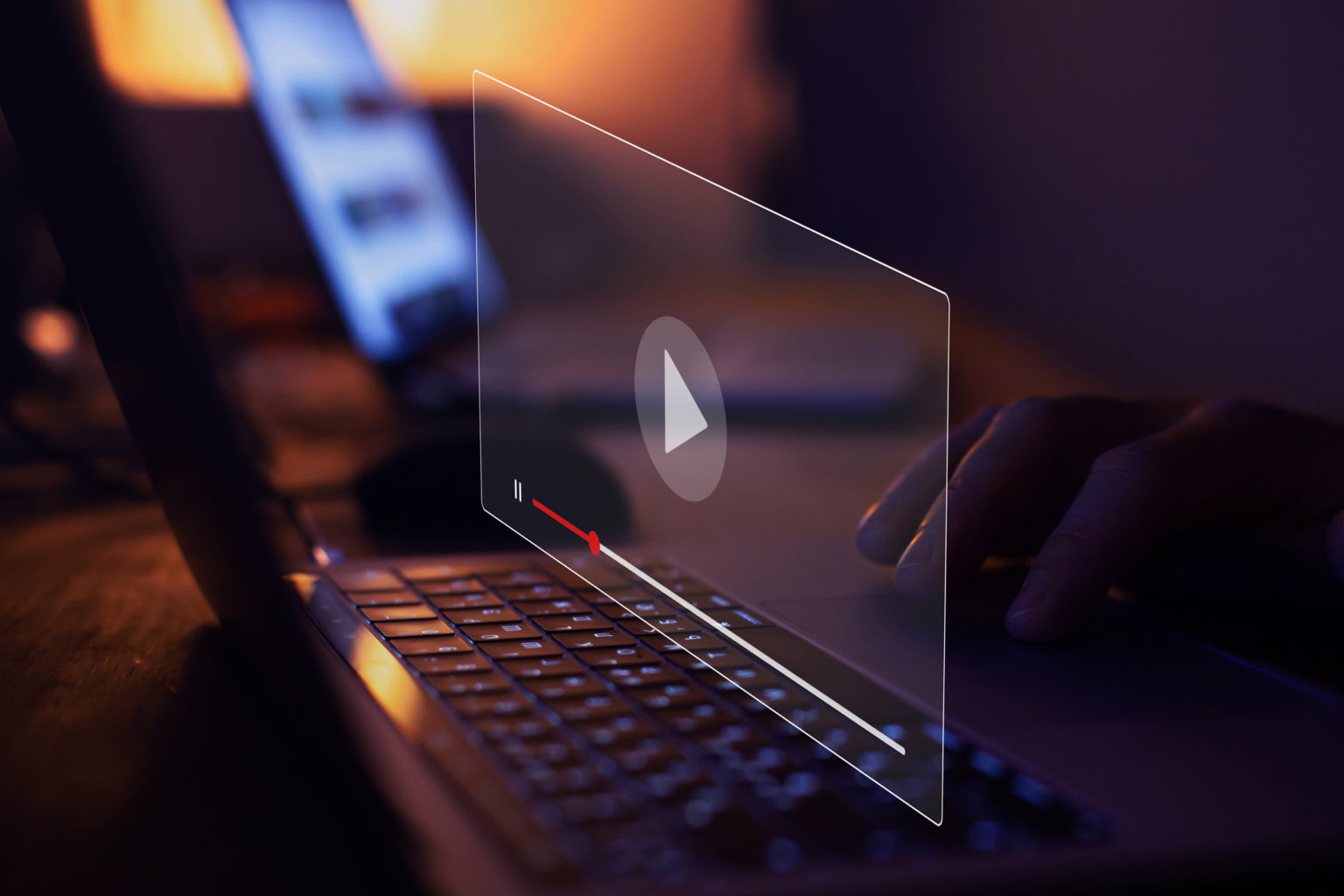 A glass video screen with a play button above a laptop