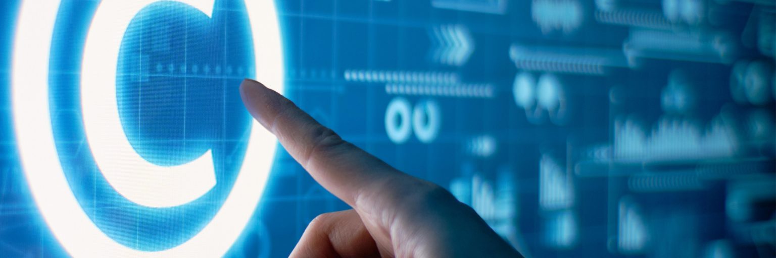 A hand touching a glowing copyright symbol on a digital display