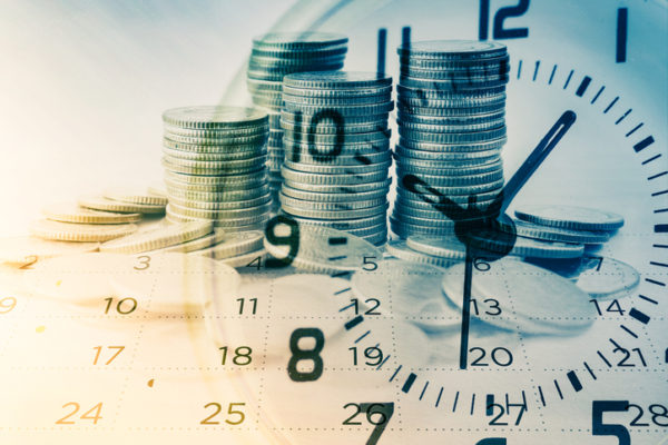 Coins in front of a clock face, representing time to file